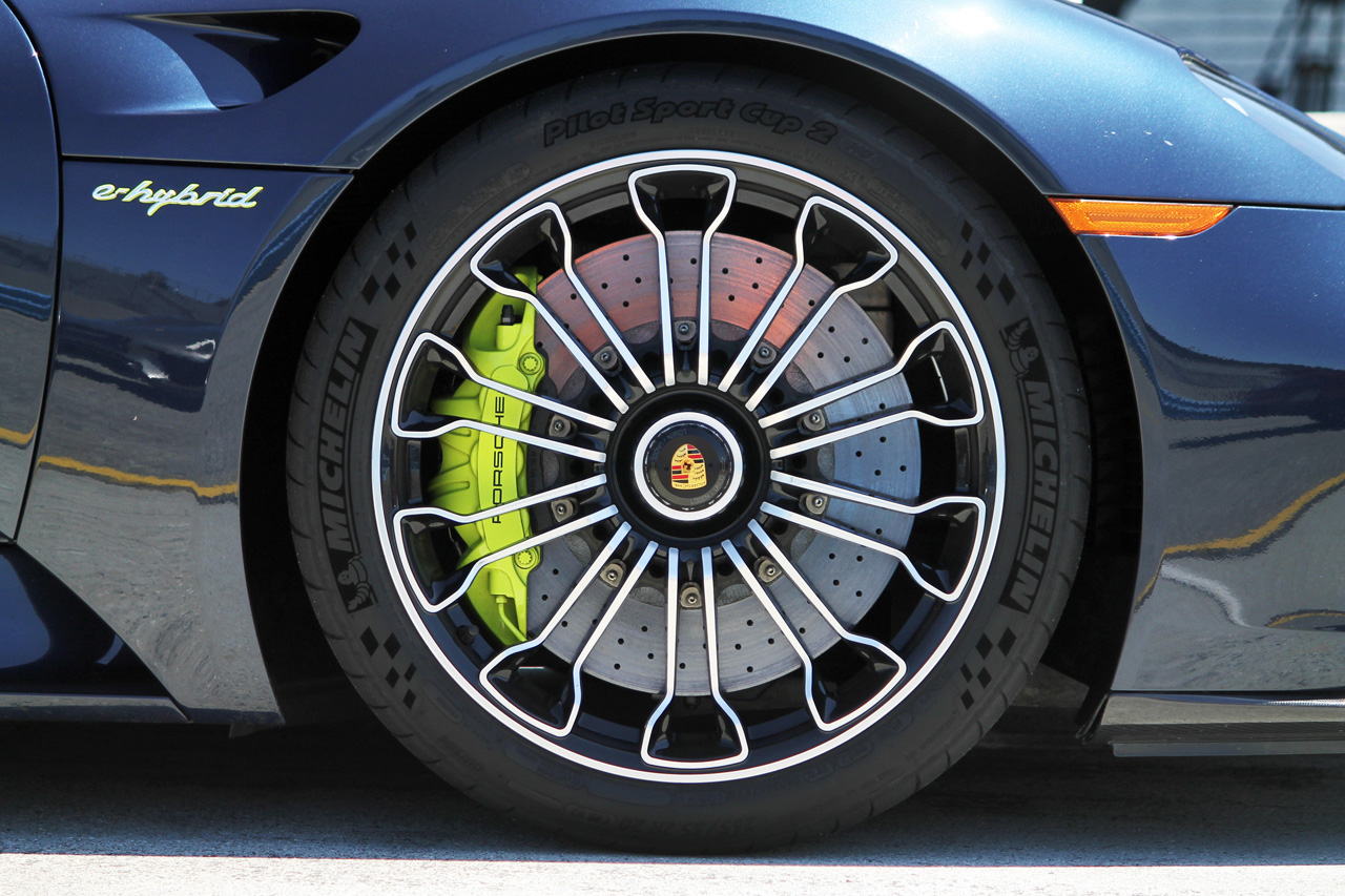 A central locking nut attaches the 918’s lightweight wheels to the car, saving weight at each corner versus a traditional multi-nut design that requires more hardware and larger wheel hubs. The wheels cover massive two-piece, internally-ventilated carbon-ceramic rotors the size of trash-can lids, and Porsche’s hybrid signature electric-green calipers provide mechanical clamping force to slow things down when drivers exceed the limits of the regenerative braking system.